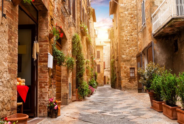 Colorful street in Pienza with many decoration flowers and trees, Tuscany, Italy