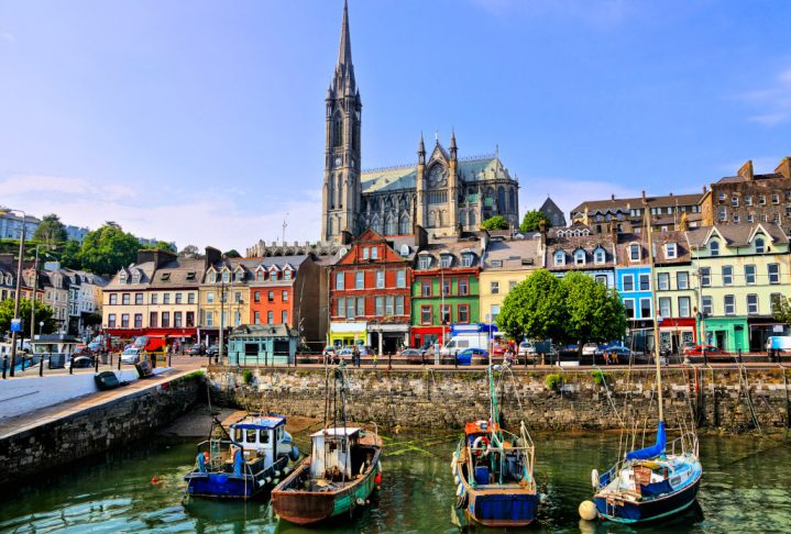 Colorful buildings and old boats with cathedral in background in the harbor of Cobh, County Cork, Ireland