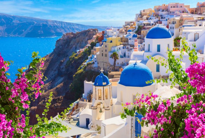 Santorini island, Greece. Oia town traditional white houses and churches with blue domes over the Caldera, Aegean sea.