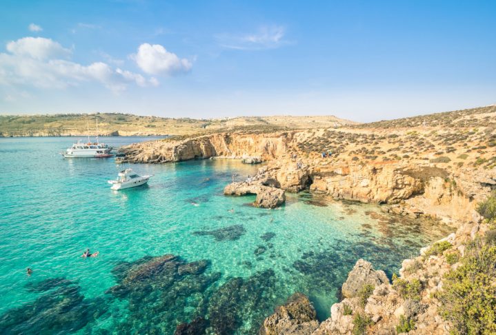 The world famous Blue Lagoon in Comino island - Mediterranean nature wonder in the beautiful Malta - Unrecognizable international tourist people and snorkeling divers - Exclusive travel destinations