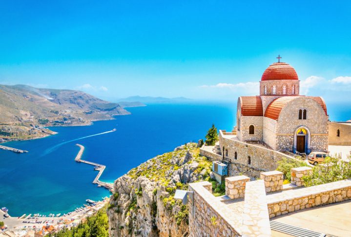 Amazing view on remote church with red roofing on the Cliff of the sea, Greece